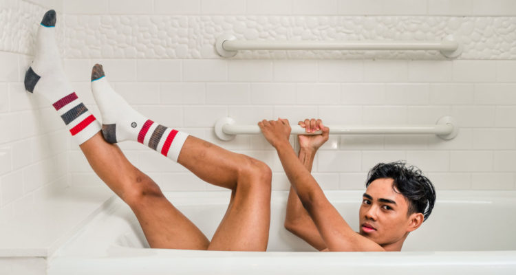 boy in classic tube socks laying in bathtub