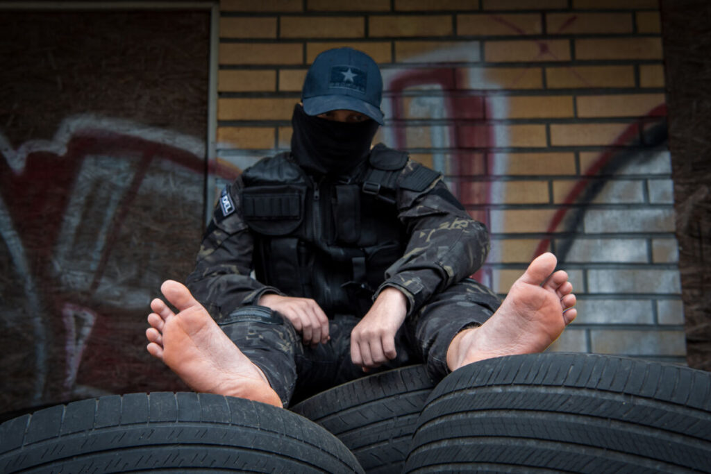 Man sitting in military uniform with exposed feet