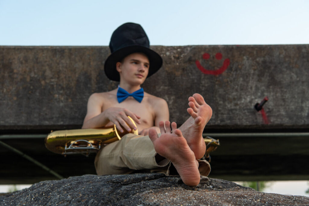 resting barefoot saxophone player with a blue bowtie and tophat