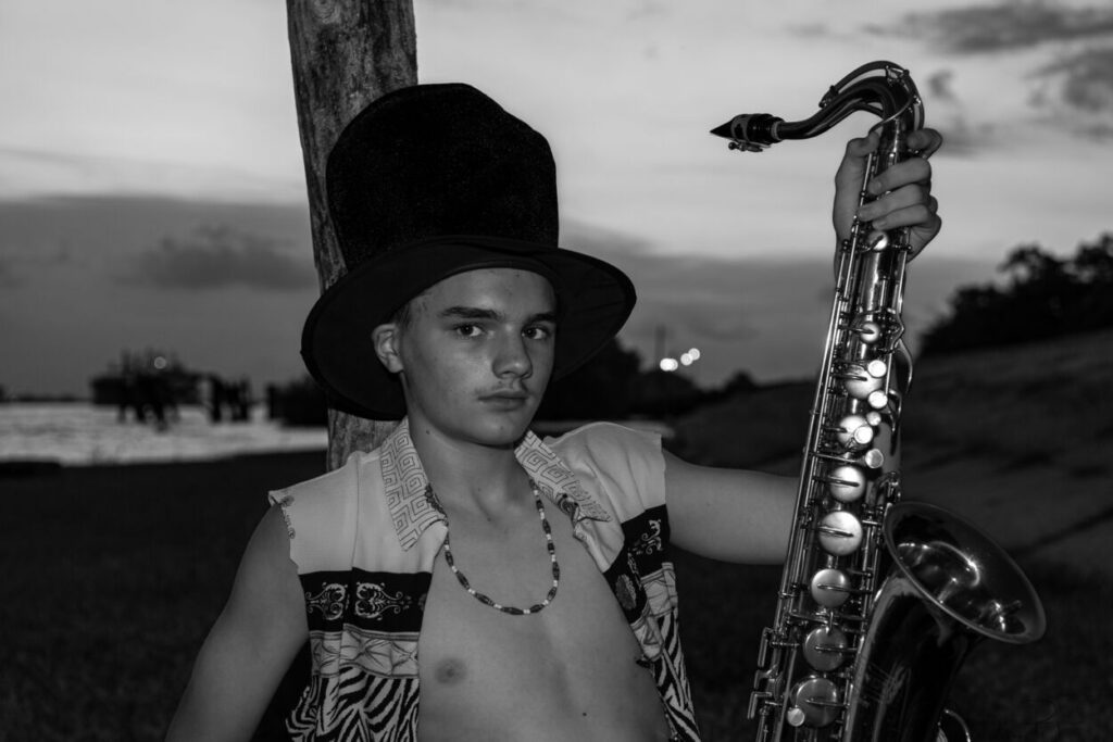 monochromatic saxophone player with a vest and bead necklace