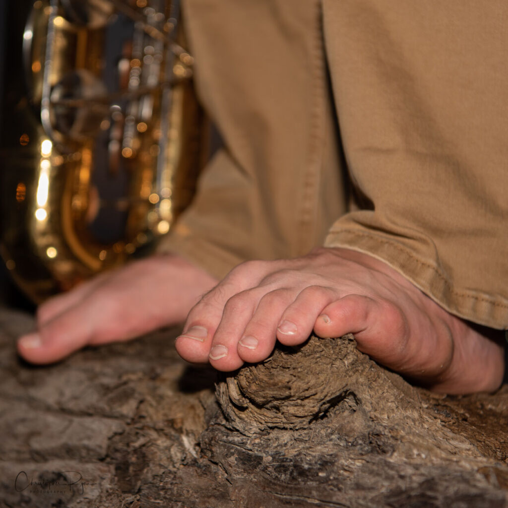 feet with grey khakis and a saxophone in the background