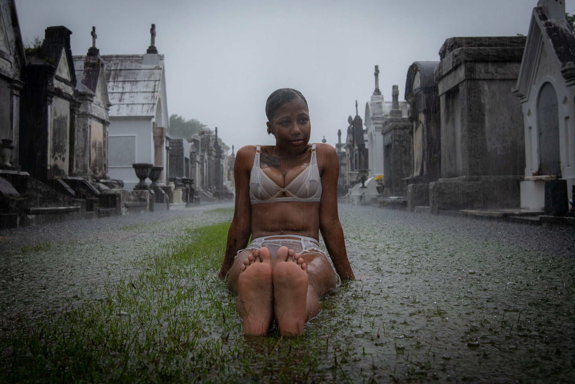 Woman sitting on the grass in a historic, misty cemetery.